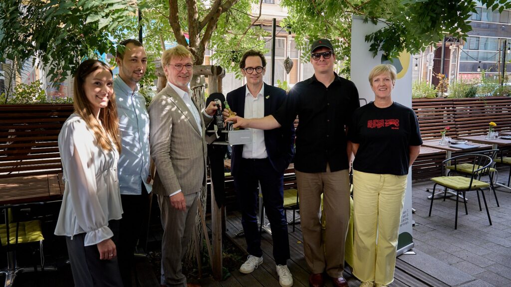 Gruppenfoto von Lorena Riegler, Erwin Lehner, den Bezirksvorstehern Markus Reiter und Martin Fabisch, dem Künstler GOLIF sowie Silke Grell bei der Präsentation der Pfandkellner*innen-Initiative.