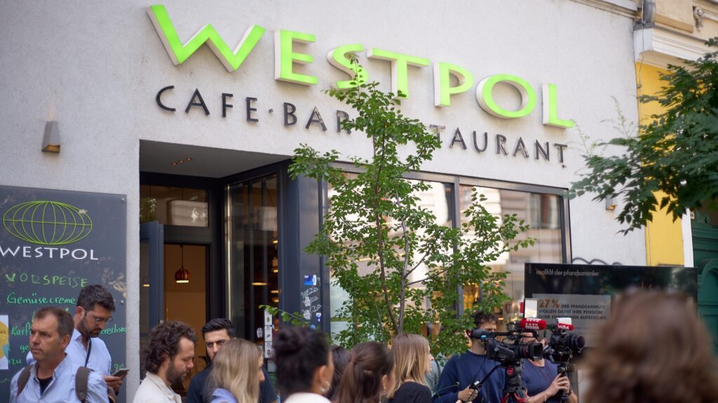 Pressekonferenz der GOLIF-Pfandkellner*innen-Initiative vor dem Restaurant Westpol in der Lerchenfelder Straße mit Medienvertreter:innen und TV-Kameras.